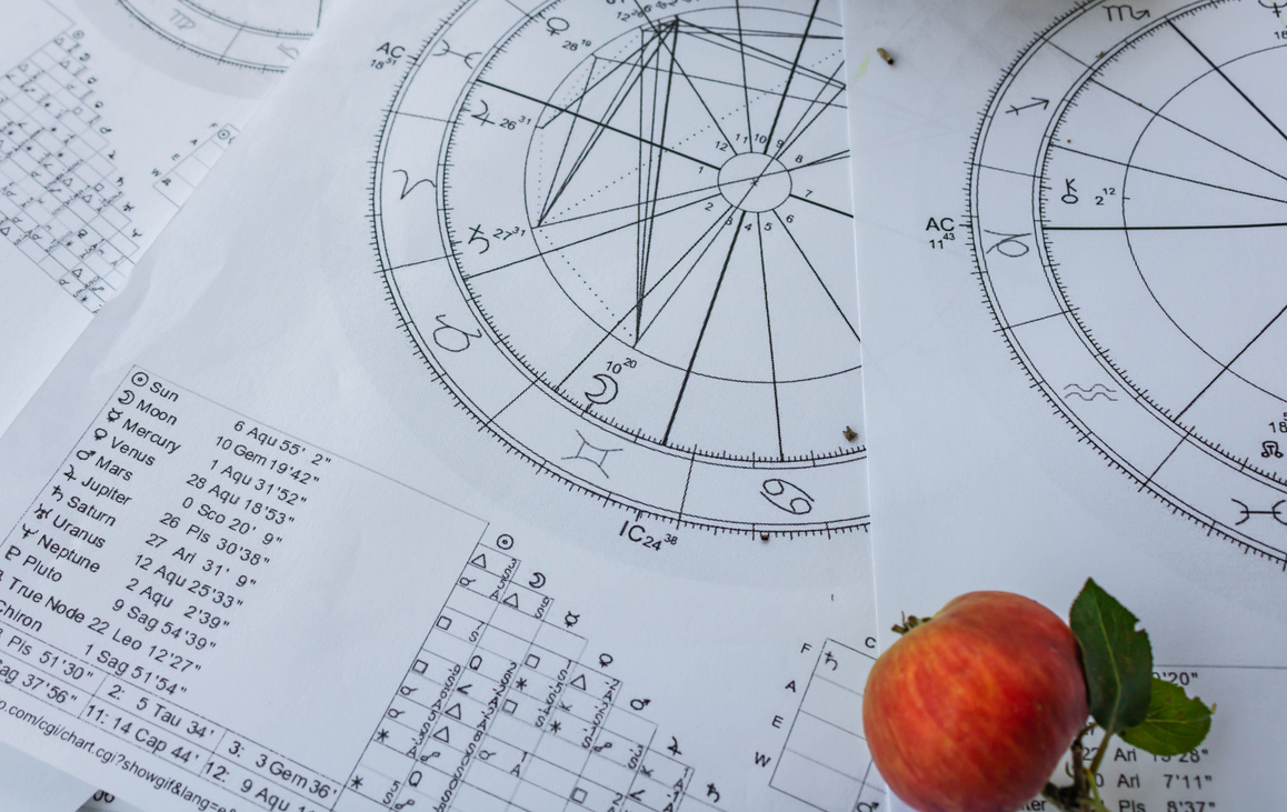 Printed birth charts with a small red apple in the foreground